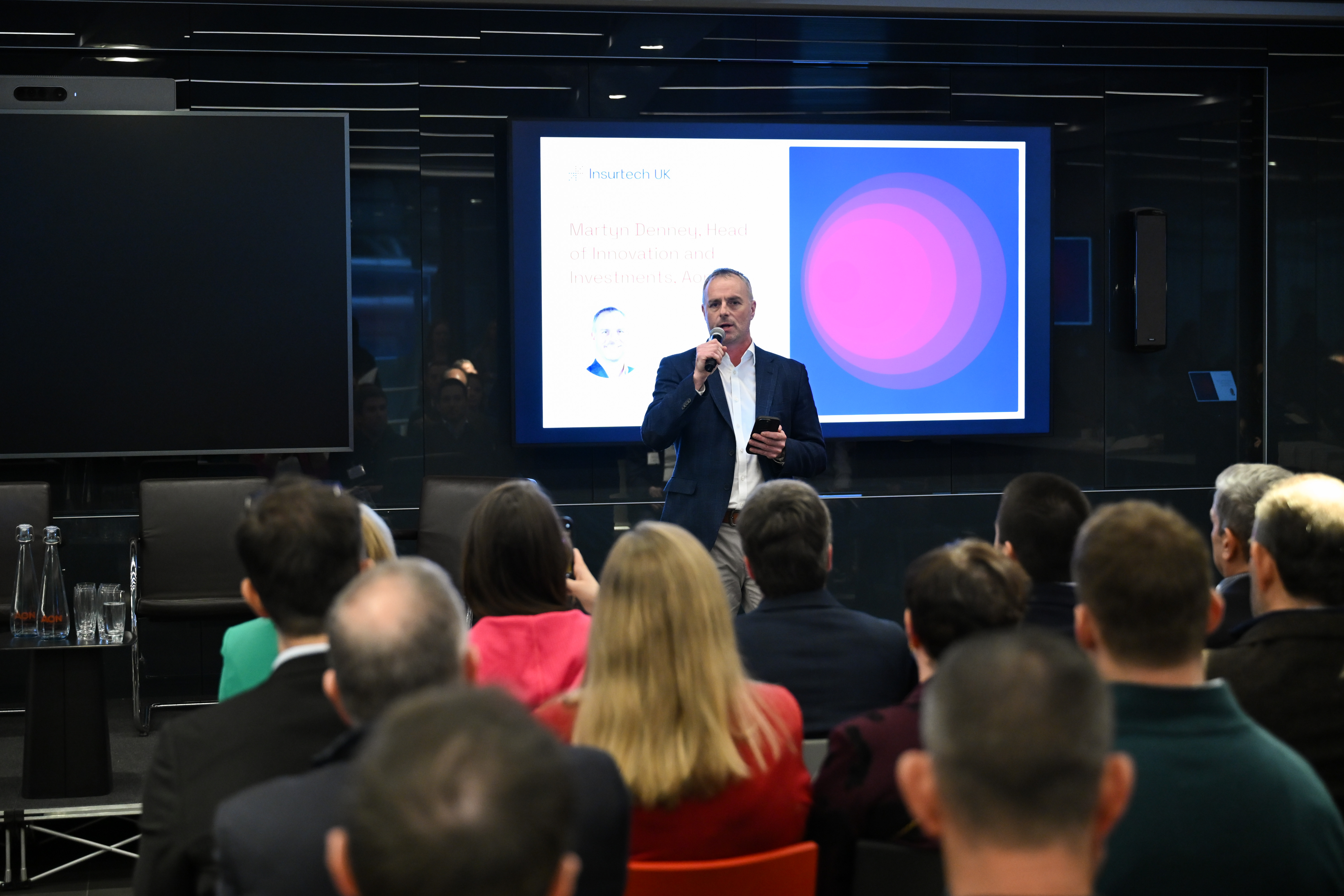Man on stage in front of audience with microphone